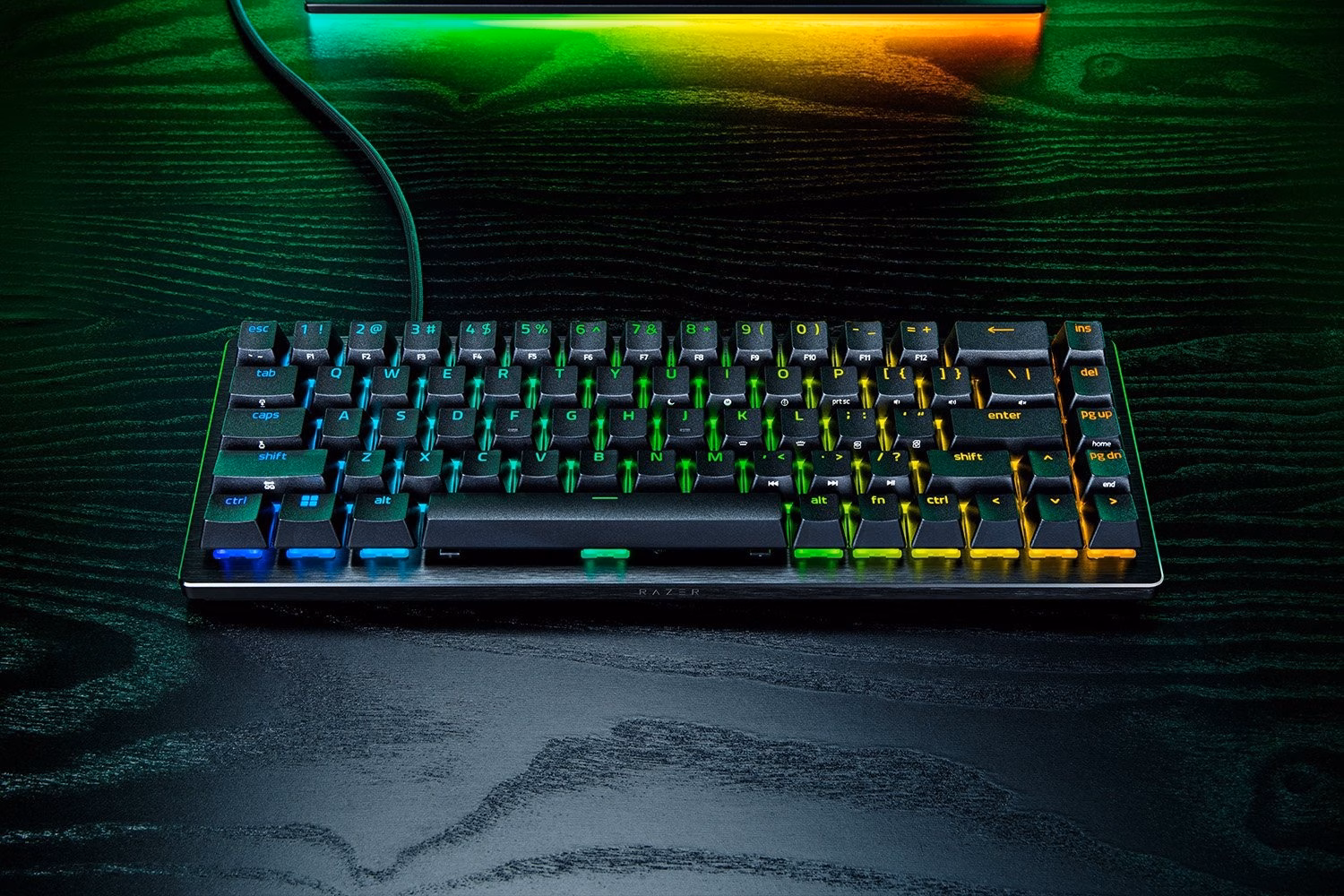 Must Razer Huntsman V3 HE mänguklaviatuur tumedal puitlaual monitori ees