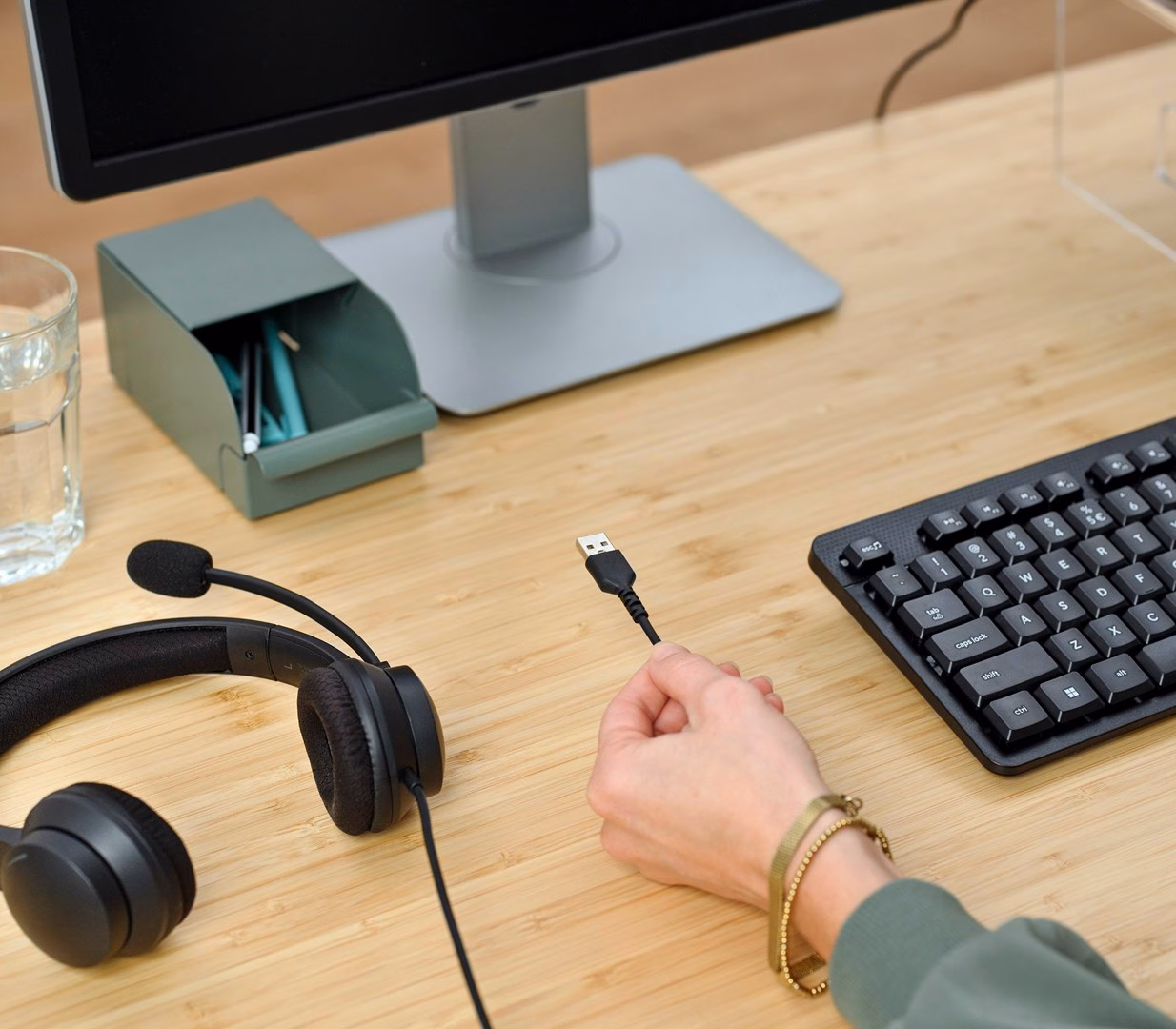 Trust HS-260 peakomplekti USB-A-pistik käes, peakomplekt laual klaviatuuri kõrval